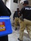 FILE - Policemen escort members of a polio vaccination team during a door-to-door vaccination campaign in Karachi, Pakistan, June 28, 2022. Two policemen escorting polio workers were killed when gunman opened fired in the town of Gomal on Aug. 16, 2022.