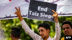 FILE - A demonstrator holds a sign reading in English "end Taiz siege" demanding the end of a yearslong blockade of the area imposed by Yemen's Houthi rebels on the Yemeni city, May 25, 2022. 