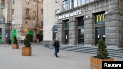 FILE - A man walks past a closed McDonald's restaurant in central Kyiv, Ukraine, February 25, 2022. On Aug. 11, 2022, the company announced it plans to reopen some of its restaurants in the country that have been closed since the Russian invasion. 