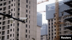 上海一处正在修建的公寓楼盘旁竖立着一个监控摄像头。（2022年7月20日）
