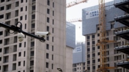 资料照：上海一处正在修建的公寓楼盘旁竖立着一个监控摄像头。（2022年7月20日）