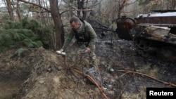 ARCHIVO - Un zapador militar recoge partes sin explotar de una bomba de racimo que quedó después de la invasión rusa cerca de la aldea de Motyzhyn, en la región de Kiev, Ucrania, el 10 de abril de 2022.