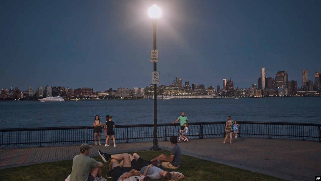 FILE - People spend time at the park at dusk during a summer heat wave, July 21, 2022, in Hoboken, New Jersey. The continental U.S. in July set a record for overnight warmth, providing little relief from the day’s sizzling heat, meteorologists said.