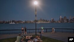 FILE - People spend time at the park at dusk during a summer heat wave, July 21, 2022, in Hoboken, New Jersey. The continental U.S. in July set a record for overnight warmth, providing little relief from the day’s sizzling heat, meteorologists said.