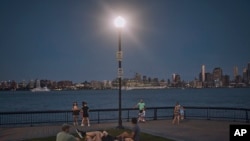 ARCHIVO - La gente pasa tiempo en el parque al anochecer durante una ola de calor de verano, el 21 de julio de 2022, en Hoboken, Nueva Jersey.