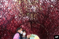 FILE - A couple wearing face masks takes a selfie photo inside a tunnel made with hot red peppers during H.O.T Festival in Seoul, South Korea, Aug. 29, 2022. (AP Photo/Ahn Young-joon)
