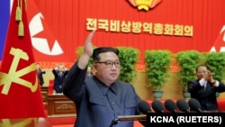 김정은(가운데) 북한 국무위원장이 10일 평양에서 열린 '전국비상방역총화회의' 연단에 나와 오른손을 들어올리고 있다. 