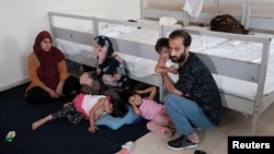 FILE - A migrant family from Afghanistan, caught by Turkish security forces after crossing illegally into Turkey from Iran, is seen in their room at a migrant processing center in the border city of Van, Turkey, Aug. 22, 2021.