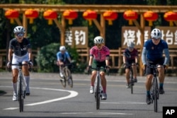 Members of the Qiyi bicycle club ride along a rural road during a group ride through the Baihe River Canyon in the northern outskirts of Beijing, Wednesday, July 13, 2022. (AP Photo/Mark Schiefelbein)