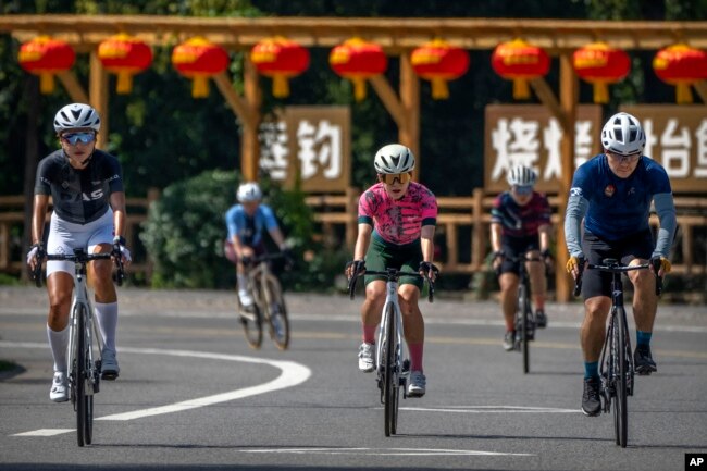 Members of the Qiyi bicycle club ride along a rural road during a group ride through the Baihe River Canyon in the northern outskirts of Beijing, Wednesday, July 13, 2022. (AP Photo/Mark Schiefelbein)