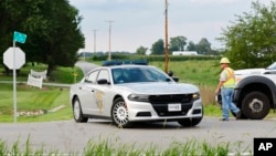A Clinton County employee helps direct traffic as an Ohio State Highway Patrol vehicle leaves the scene where an armed man was shot and killed by police after breaching the FBI's Cincinnati field office, Aug. 11, 2022, in Wilmington, Ohio.