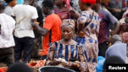 FILE - A woman counts money at Mile 12 International Market in Lagos, Nigeria, May 13, 2022.