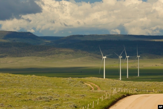 Clouds cast shadows near wind turbines at a wind farm along the Montana-Wyoming state line on Monday, June 13, 2022. The rush to build wind farms to combat climate change is colliding with preservation of one of the U.S. West's most spectacular predators, the golden eagle. (AP Photo/Emma H. Tobin)