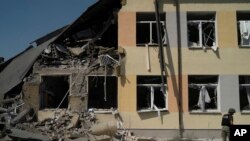 A Ukrainian serviceman stands in front of a heavily damaged school after a Russian attack in Druzhkivka, Donetsk region, eastern Ukraine, Aug. 30, 2022. 