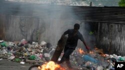 A protester kicks a burning tire during a protest in Port-au-Prince, Haiti, Aug. 22, 2022.