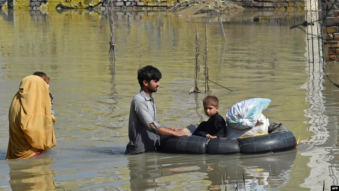A family wades through a flood hit area following heavy monsoon rains in Charsadda district of Khyber Pakhtunkhwa, Aug. 29, 2022. 