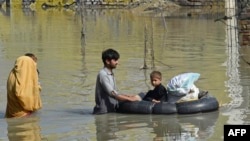 A family wades through a flood hit area following heavy monsoon rains in Charsadda district of Khyber Pakhtunkhwa, Aug. 29, 2022. 
