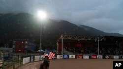 Seorang koboi perempuan membawa bendera AS sebelum dimulainya pertandingan menunggang banteng di Jackson Hole Rodeo di Jackson, Wyoming, pada 13 Agustus 2022. (Foto: AP/Jae C. Hong)