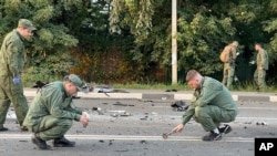 In this handout photo taken from video released by Investigative Committee of Russia on Sunday, Aug. 21, 2022, investigators work on the site of explosion of a car driven by Daria Dugina outside Moscow. (Investigative Committee of Russia via AP)