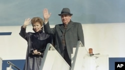 FILE - Mikhail Gorbachev with wife, Raisa, wave before boarding a plane on departure from New York's John F. Kennedy Airport, December 1988.