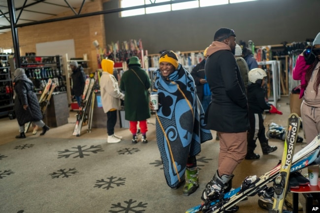 Visitors to the Afriski ski resort near Butha-Buthe, Lesotho, one wearing a traditional Basutu blanket, wait to rent ski gear Saturday July 30, 2022. (AP Photo/Jerome Delay)