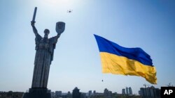 FILE - A drone carries a national flag in front of Ukraine's Motherland Monument in Kyiv, Ukraine, Aug. 24, 2022. 