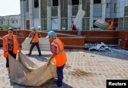 Workers remove debris outside the local administration headquarters damaged by recent shelling in the course of Ukraine-Russia conflict in the Russian-controlled city of Enerhodar in the Zaporizhzhia region, Ukraine, Aug. 31, 2022.