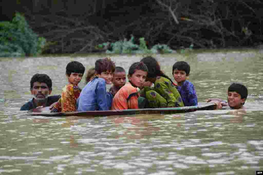 A man and a youth use a satellite dish to move children across a flooded area after heavy monsoon rainfalls in Jaffarabad district, Balochistan province, Pakistan.