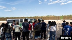 Migrantes que buscan asilo esperan ser transportados por agentes de Aduanas y Protección Fronteriza, después de cruzar el río Grande desde México, en Eagle Pass, Texas, EEUU, el 26 de julio de 2022.