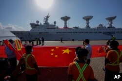 Pekerja pelabuhan Sri Lanka memegang bendera nasional China saat menyambut kapal penelitian China, Yuan Wang 5, setibanya di Pelabuhan Internasional Hambantota di Hambantota, Sri Lanka, Selasa, 16 Agustus 2022.(AP/Eranga Jayawardena)