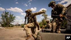 FILE - Ukrainian servicemen of "Fireflies" reconnaissance team jump from the trunk of pickup to take their position at the frontline in Mykolaiv region, Ukraine, Aug. 8, 2022.