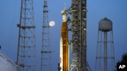 ARCHIVO - La luna se pone frente al cohete Artemis de la NASA con la nave espacial Orion a bordo en la plataforma 39B en el Centro Espacial Kennedy, el miércoles 15 de junio de 2022, en Cabo Cañaveral, Florida.