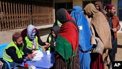 FILE - Afghans register to receive food supplies during a distribution of humanitarian aid for families in need, in Kabul, Afghanistan, Feb. 16, 2022.