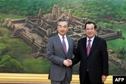 FILE - Cambodia's Prime Minister Hun Sen (R) shakes hands with China's Foreign Minister Wang Yi (L) during a meeting at the Peace Palace in Phnom Penh, on August 3, 2022. (Photo by Kok KY / CAMBODIA'S GOVERNMENT CABINET / AFP)