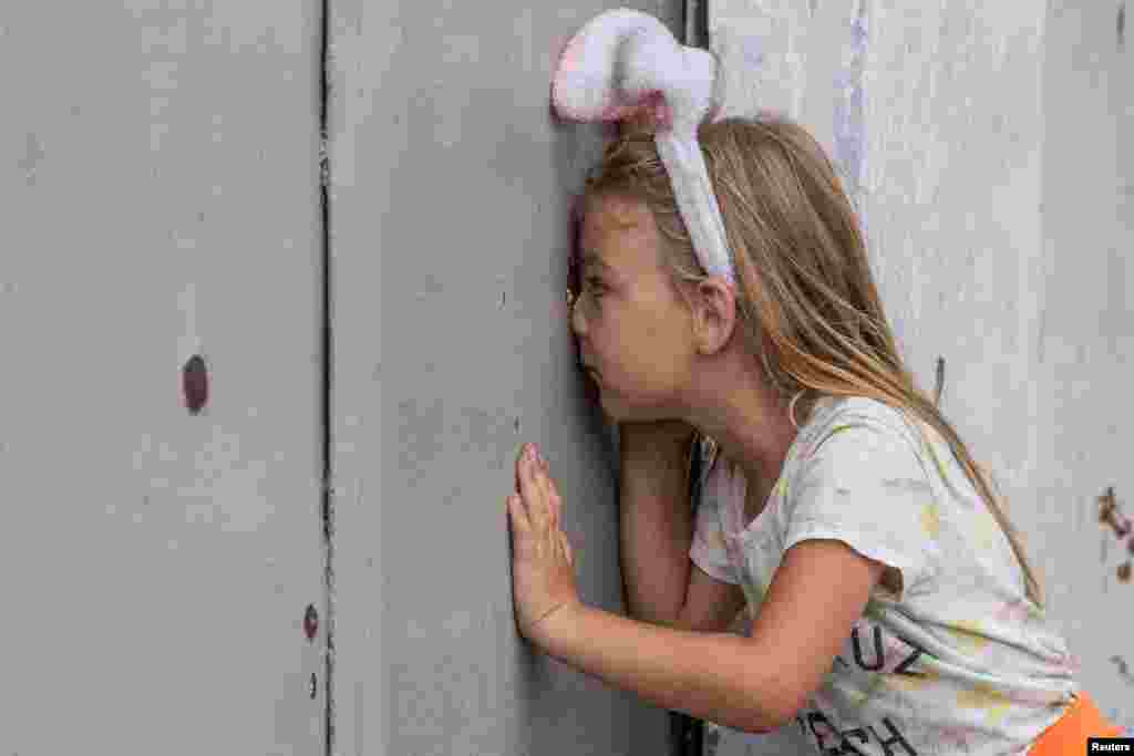 Anhelina looks through a shrapnel hole in a fence after a recent Russian military strike in Mykolaiv as Russia&#39;s attack on Ukraine continues, in Mykolaiv.