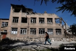 Seorang pria berjalan di dekat sekolah yang hancur, saat serangan Rusia di Ukraina berlanjut, di Toretsk, wilayah Donetsk, Ukraina 22 Agustus 2022. (REUTERS/Ammar Awad)