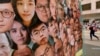 FILE - A woman walks past a banner with photos of pro-democracy activists, including Joshua Wong, center, during the anniversary of the Hong Kong handover to China from Britain in Hong Kong, July 1, 2021.