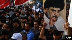 Supporters of Shiite cleric Muqtada al-Sadr carry portraits of him as they gather in the city of Nasiriyah in Iraq's southern Dhi Qar province, Aug. 12, 2022, to protest against the nomination of a rival Shiite faction for the position of prime minister.