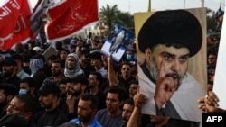 FILE - Supporters of Shiite cleric Muqtada al-Sadr carry portraits of him as they gather in the city of Nasiriyah in Iraq's southern Dhi Qar province, Aug. 12, 2022, to protest against the nomination of a rival Shiite faction for the position of prime minister. 