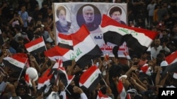 Supporters of Iraq's Coordination Framework lift a placard depicting, from left, Iraqi top Shiite cleric Grand Ayatollah Ali al-Sistani, slain Iraqi commander Abu Mahdi al-Muhandis, and late Iraqi Shiite cleric Mohammed Baqir al-Sadr, outside Bagdad's Green Zone.