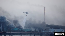 Un helicóptero arroja agua sobre la zona donde explotaron los tanques de almacenamiento de combustible cerca del puerto de superpetroleros de Cuba en Matanzas, Cuba, el 9 de agosto de 2022.