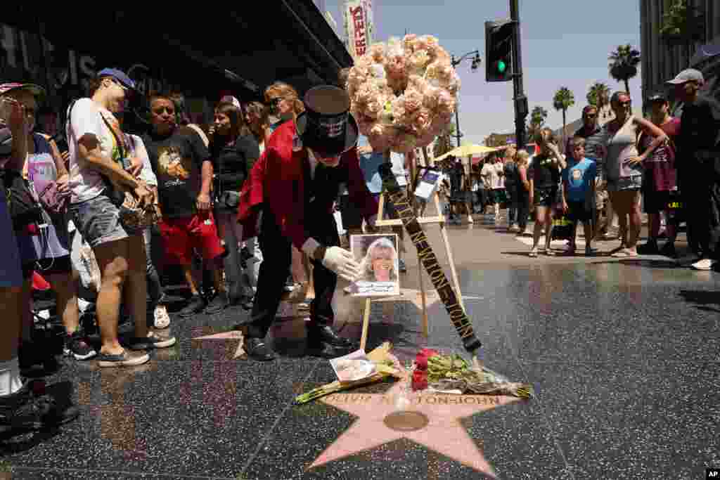 Gregg Donovan, middle, former ambassador of Beverly Hills Fans, honors actor and singer Olivia Newton-John with flowers on her Hollywood Walk of Fame star in Los Angeles, Aug. 8, 2022. The Grammy-winning superstar has died at the age of 73.