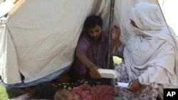 Rubina Bibi, right, sits near to her family after take refuge at a camp after fleeing her flood-hit homes, in Charsadda, Pakistan, Aug. 30, 2022.