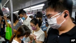 FILE - Commuters ride on a subway train during the morning rush hour in the central business district in Beijing, Aug. 9, 2022.