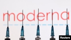 FILE - Syringes with needles are seen in front of a displayed Moderna logo in this illustration taken Nov. 27, 2021. 