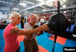 Parkinson's patient Jim Coppula gets some pointers from his daughter Ellen as he works out on a bag during his Rock Steady Boxing class in Costa Mesa, California September 18, 2013. (REUTERS/Mike Blake)