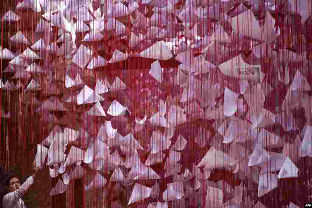 A visitor looks at an art installation called &quot;Tell me your Story&quot; by Japanese artist Chiharu Shiota in Pristina, at the 14th edition of the European Nomadic biennale held in Kosovo. (Photo by Armend NIMANI / AFP)