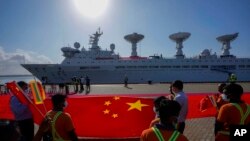 Pekerja pelabuhan Sri Lanka memegang bendera nasional China untuk menyambut kedatangan kapal penelitian "Yuan Wang 5" di Pelabuhan Internasional Hambantota, Sri Lanka, Selasa, 16 Agustus 2022.