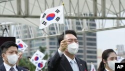 El presidente de Corea del Sur, Yoon Suk Yeol, ondea una bandera nacional en un acto para celebrar el Día de la Liberación Coreana del régimen colonial japonés en 1945, en la plaza ante la oficina presidencial en Seúl, Corea el Sur, el lunes 15 de agosto de 2022. 