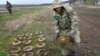 FILE - An interior ministry sapper collects mines on a mine field after recent battles in Irpin close to Kyiv, Ukraine, April 19, 2022. 